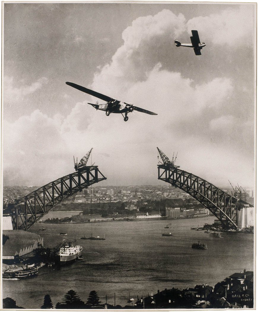Sydney Harbour Bridge during construction, 1930, with two aeroplanes, Charles Ulms "Southern Sun" & a Gypsy Moth photomontage by Edward Searl