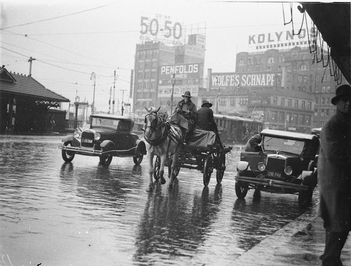 A dray a Ford Model A coupe 1928 model and a Morris Oxford Roadster 1932 model in summer rain Railway Square, Sydney (1935)