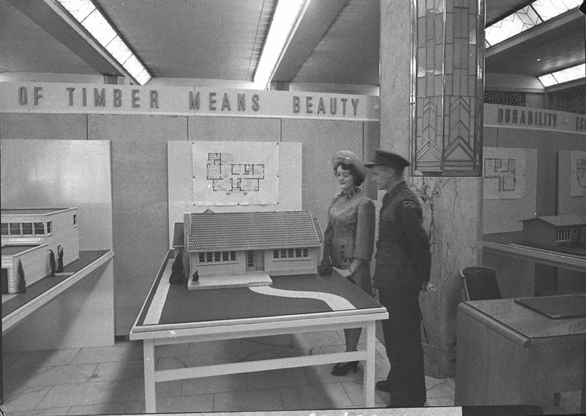 Airman and woman admire a model of a cottage Timber Homes Exhibition (1944)