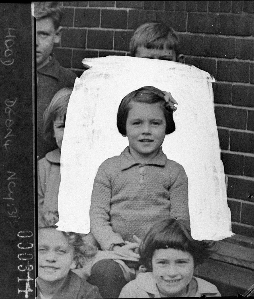 An unidentified small girl with a boy holding a white background behind her (1925–57)