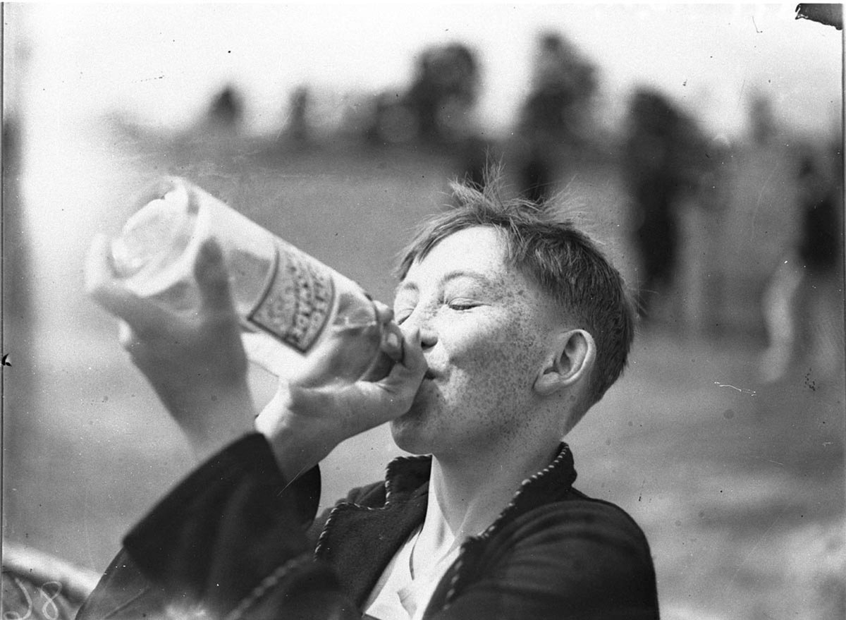 Boy drinking softdrink from bottle at school sports (1934)