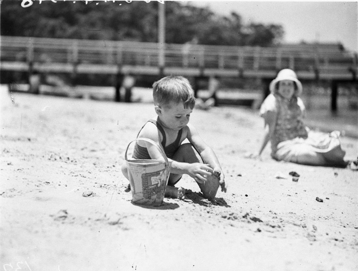 Boy playing with bucket in the sand at the Mick Simmons Radio Club picnic (1934)