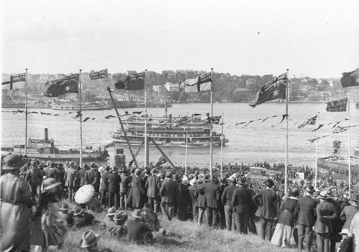 Crowds cheer from flag bedecked Dawes Point Two ferries and a North Sydney vehicular ferry pass by (1925)