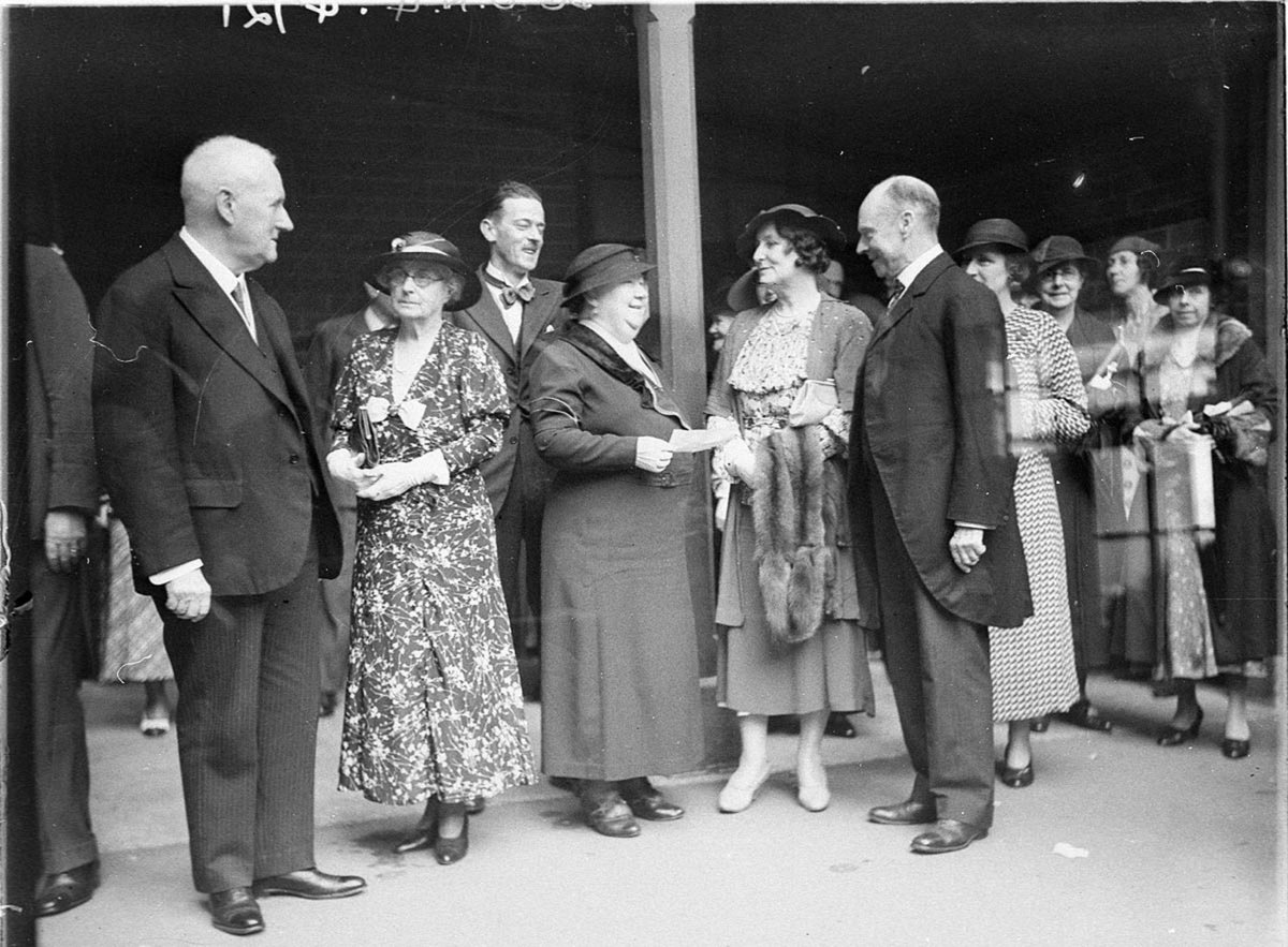 Group of unidentified VIP men and women Woman holding a fur stole and man in frockcoat (c. 1934)