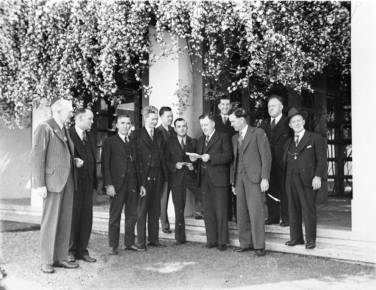 Labor MHR Jack Beasley reads a document to other ALP MHRs 14th Parliament Eddie Ward 5th from left and Jock Garden behind Beasley (1934)