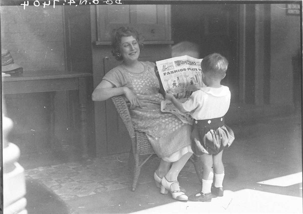 Musical comedy star Dorothy Brunton showing Sid Nicholls Fashionplate Fanny in the childrens section of The Sun newspaper to a small boy (1925)