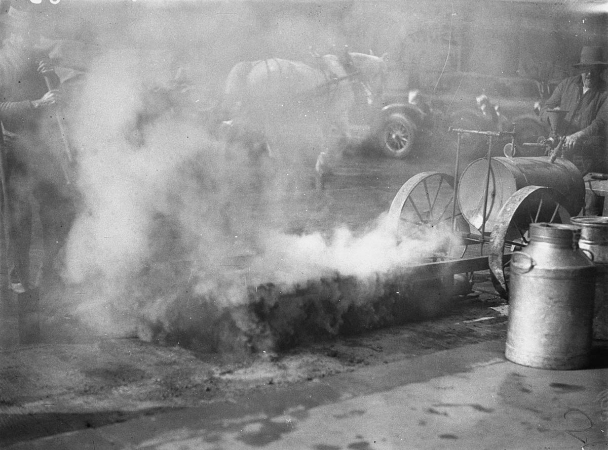 Smoke billowing from hotmix generator new hotbitumen paving process on city street (1934)