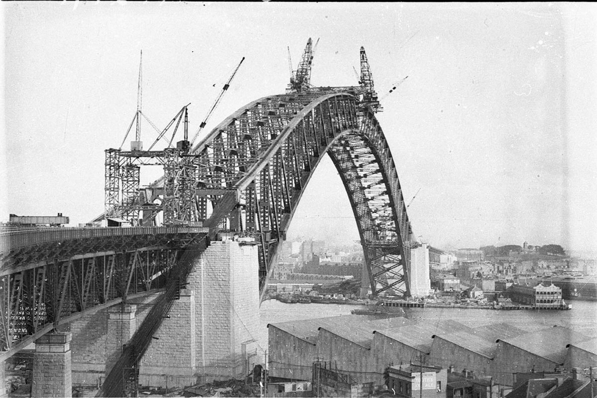 View of the Sydney Harbour Bridge from the north side showing the arch completed and Dorman Longs workshop in foreground (1930)