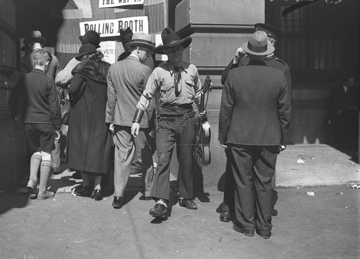 Tex Morton in full cowboy rig and guitar arrives to vote, Sydney Town Hall, Sydney city centre (1934)