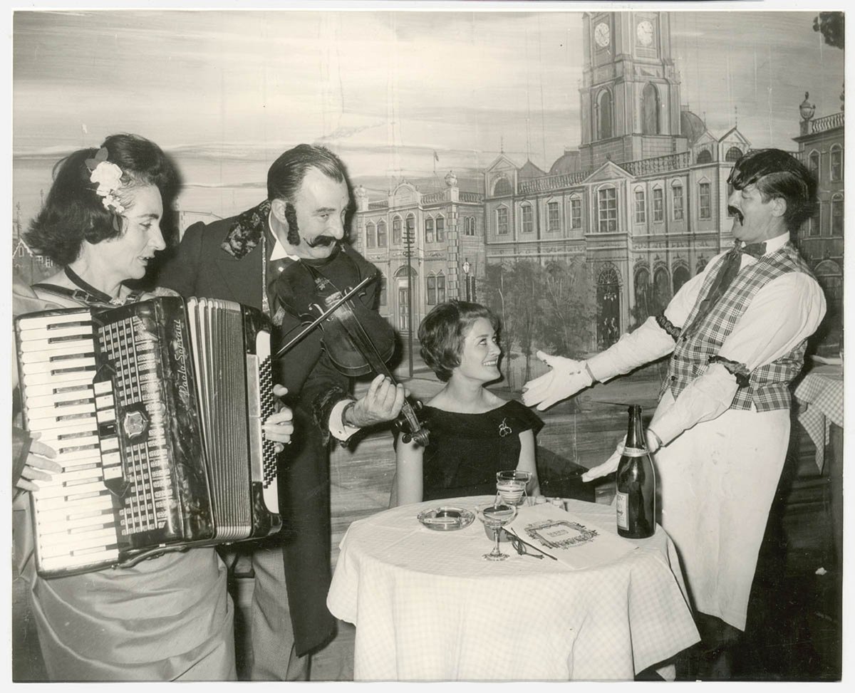 Elizabeth Connelly, TWA air hostess froom New York serenaded by head waiter with Mr and Mrs George Miller playing the violin and accordion respectively, Music Hall Restaurant, Apr 1965, Neutral Bay