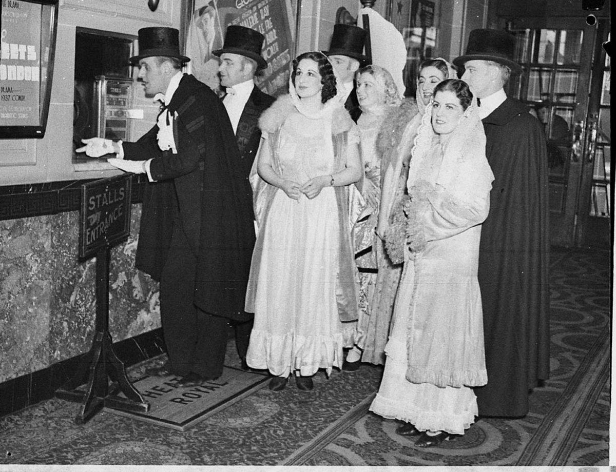 Group in evening dress at the box office of the Theatre Royal for "Lights of London" (taken for J.C. Williamson), Sydney, 8 July 1937 - photographer Sam Hood, Sydney city centre