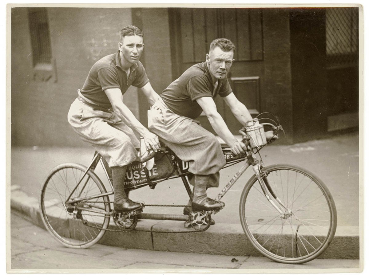 Two men in plus-fours on a tandem, by Sam Hood (1936)