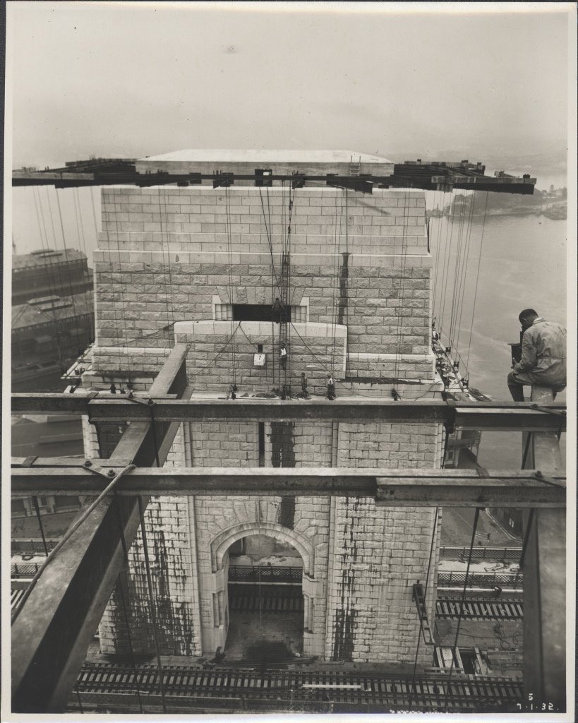 Photographer perched on ironwork of Sydney Harbour Bridge, 1932