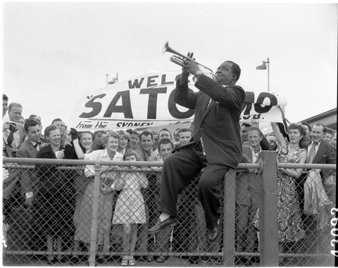 Louis "Satchmo" Armstrong plays for fans on arrival at Mascot, Sydney, 27 October, 1954