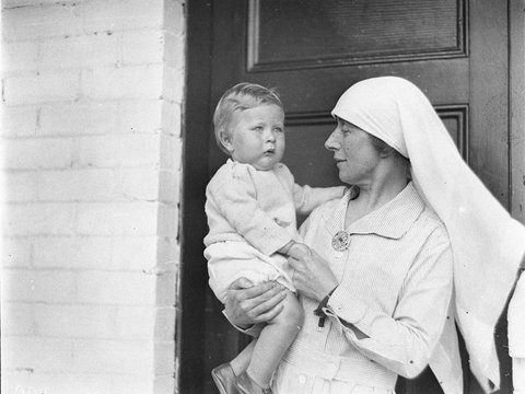 A nurse holds one of the baby entrants, 1930s