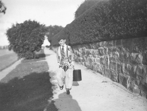 A schoolboy wearing cowboy chaps and vest over his school uniform, 1934