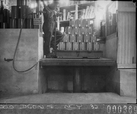 A workman stacking a pallet of paint cans on the elevator, 1945