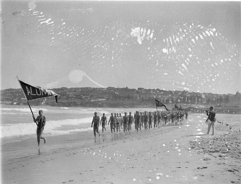 Alumni team march past Astra Hotel in background, 1930s