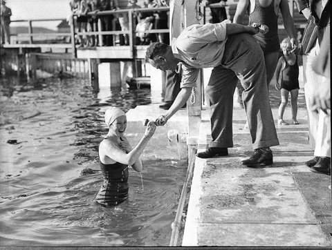 An official hands a young woman swimmer a token Tramway swimming at Coogee Aquarium, 1935