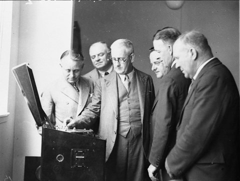AWA marine supt WH Phillip demonstrates the automatic SOS machine to Commonwealth officials and trade unions who were protesting against the machine, 1934