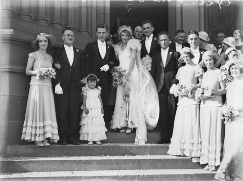 Bridal couple and guests on steps of church, 1930s