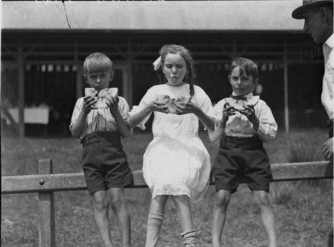 Children two boys and a girl eating slices of watermelon, 1930s