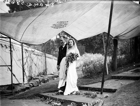 Couple arrive at marquee under canvas protection from the rain WhitneyFriend wedding, 1934