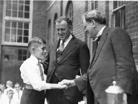 Director of Education G Ross Thomas shakes hands with the dux of Drummoyne Primary School, 1934