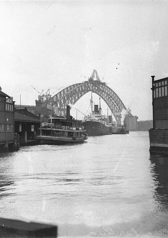 Ferry Lady Denman pulls into Circular Quay with two KLNM ships in background framed by the completed arch of the Bridge, 1930–32