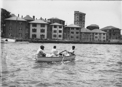 Four crewmen row out to their yacht in a dinghy, 1930s