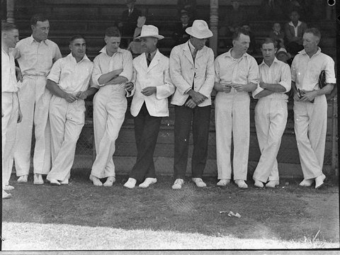 Group of eight cricketers and two umpires sheltering during rain at Sydney Cricket Ground, 1935