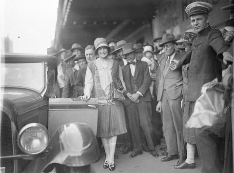 Haymarket Theatre commissionaire holds back the crowd as the first Miss Australia Beryl Mills gets into her new Chrysler convertible, 1927