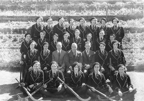 Large group of 25 schoolgirl hockey players with their three male teachers, 1930s