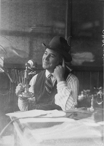 Man wearing Stetson hat talking on candlestick telephone, c. 1931