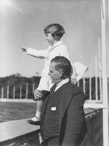 Mr Page of Concord holds his daughter Gloria up on the seawall Botanic Gardens to see the visiting Italian cruiser, 1934
