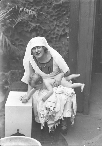 Musical comedy star Dorothy Brunton holding a nude small child grabbing the soap St Margarets Hospital, 1925