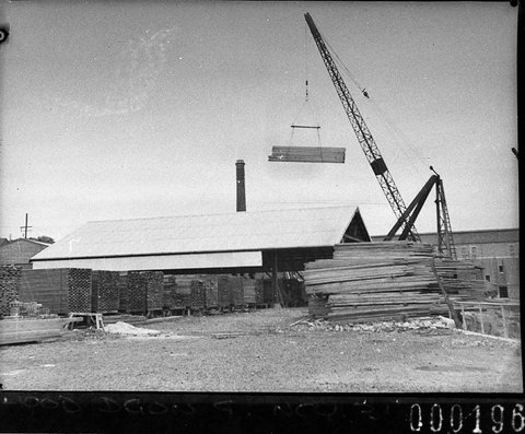 Shows crane stacking timber, 1940