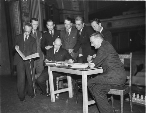 Six actors talking over their parts with musical director Andrew McCunn and stage producer, c. 1935