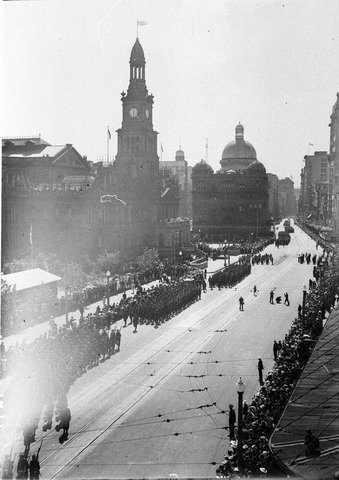 Soldiers parade along George Street past the Queen Victoria Building and Town Hall press photographers in right foreground, c. 1939