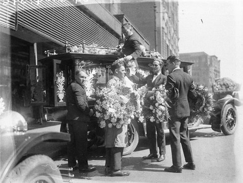 Stacking the floral tributes on the top of the hearse, c. 1930