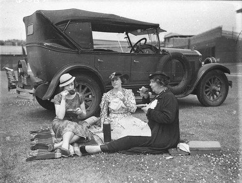 Three women cricket spectators picnicking beside a 1928 Buick during a 2nd XI cricket match between NSW and Victoria at the Sydney Cricket Ground, 1934