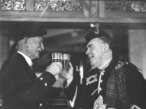 Two Highlanders clink their glasses of beer at the Highland Societys Caledonian Games, 1935