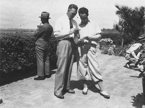 Two unidentified golfers compare scorecards, 1920s