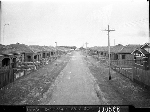 Unsealed suburban street with houses on each side from high elevation taken for Mascot Council, 1938