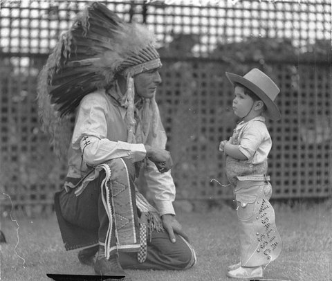 Visiting Indian Chief High Eagle talks with Johnny Schneider (aged about 3 or 4 and dressed in cowboy outfit), White City, Sydney, 11 Jan 1935 - photographer Sam Hood