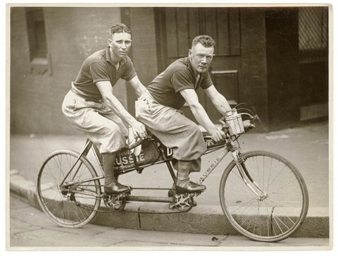 Two men in plus-fours on a tandem, by Sam Hood, 1936