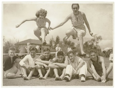Girls jump over boys seated on a sportsground, c. 1930s, by Sam Hood