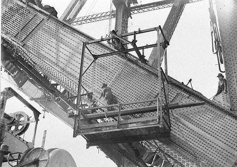 Riggers riveting the red-hot rivets on the lower outside south chord, Sydney Harbour Bridge, 1930-1931 - Sam Hood, 1930–32