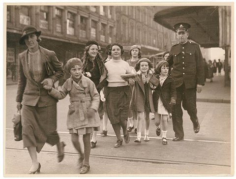 Policeman helps woman with group of girls to cross a city street, ca. 1935, from Hood Collection part II - (Children in groups and with adults, social functions, etc.), ca. 1925-ca. 1955 - Sam Hood, 1925–55