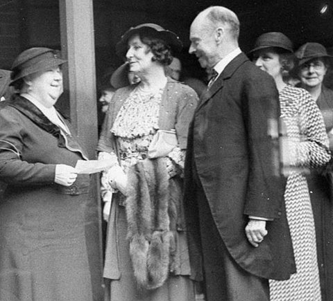 Group of unidentified VIP men and women Woman holding a fur stole and man in frockcoat (cropped), c. 1934